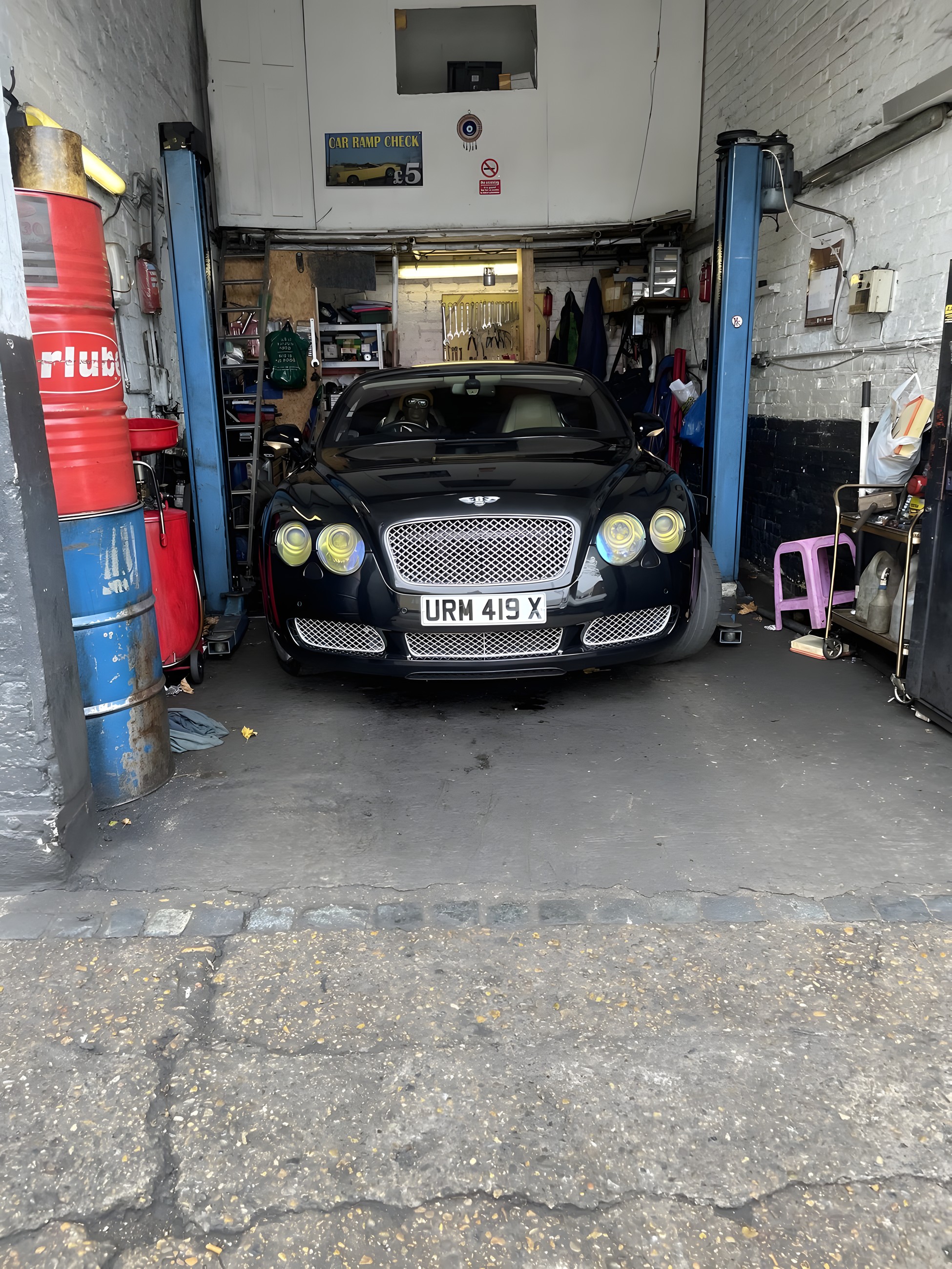 A car raised on the ramp inside the Lucky Garage workshop bay