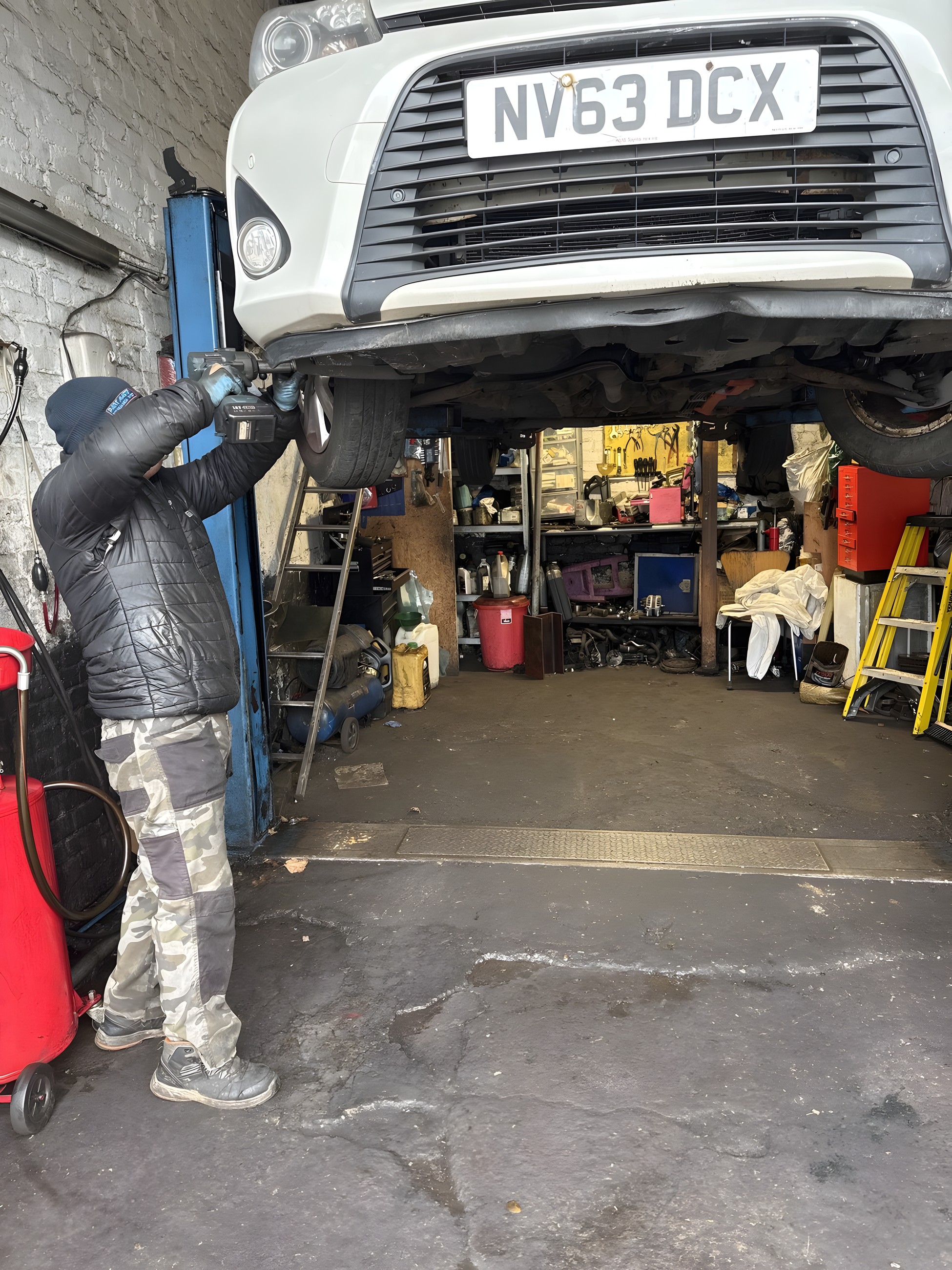 Mechanic at Lucky Garage working on a car raised on the two-post ramp